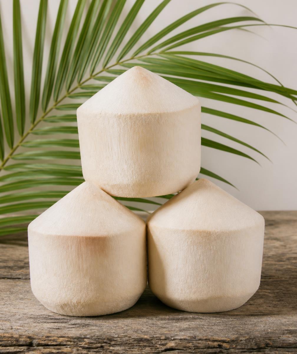 Three fresh coconuts stacked on a wooden table